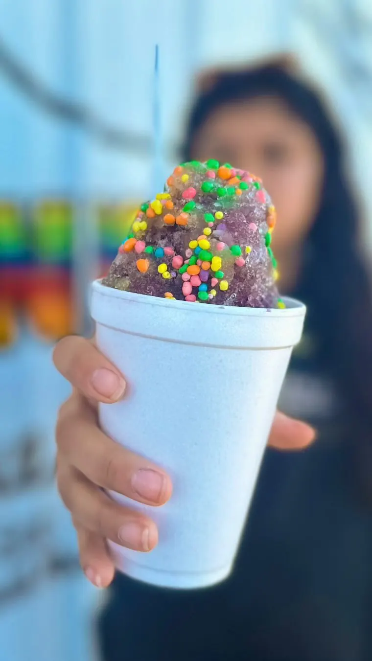 A purple snow cone covered in rainbow Nerds