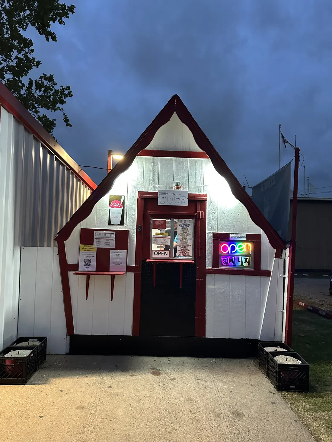 The red and white Zink's snow cone stand lit up at dusk